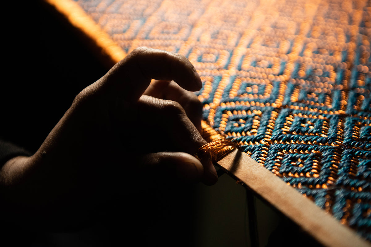 Close-up of VERDI's metal-thread weaving, copper filament interwoven with natural fiber on a manual loom